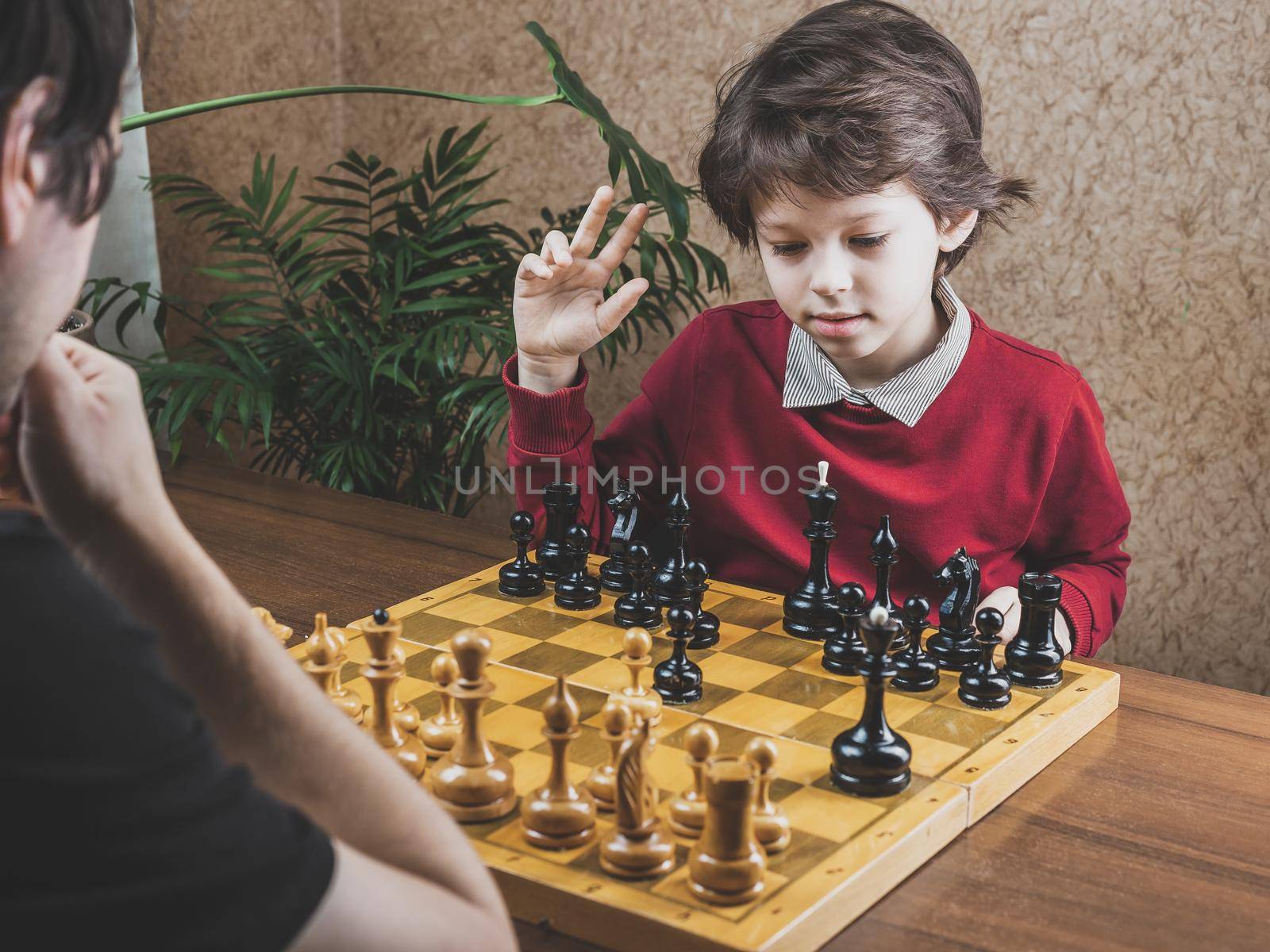 Father and son spending time together playing chess at home.
