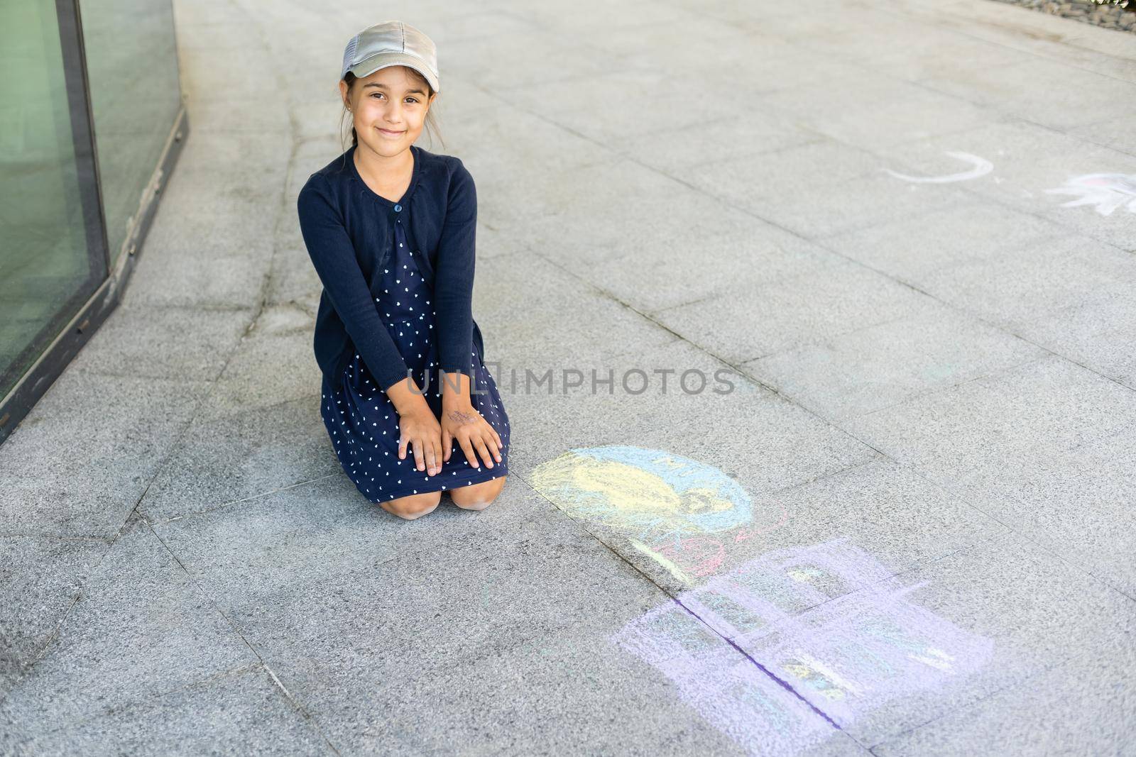 little girl draws on the pavement