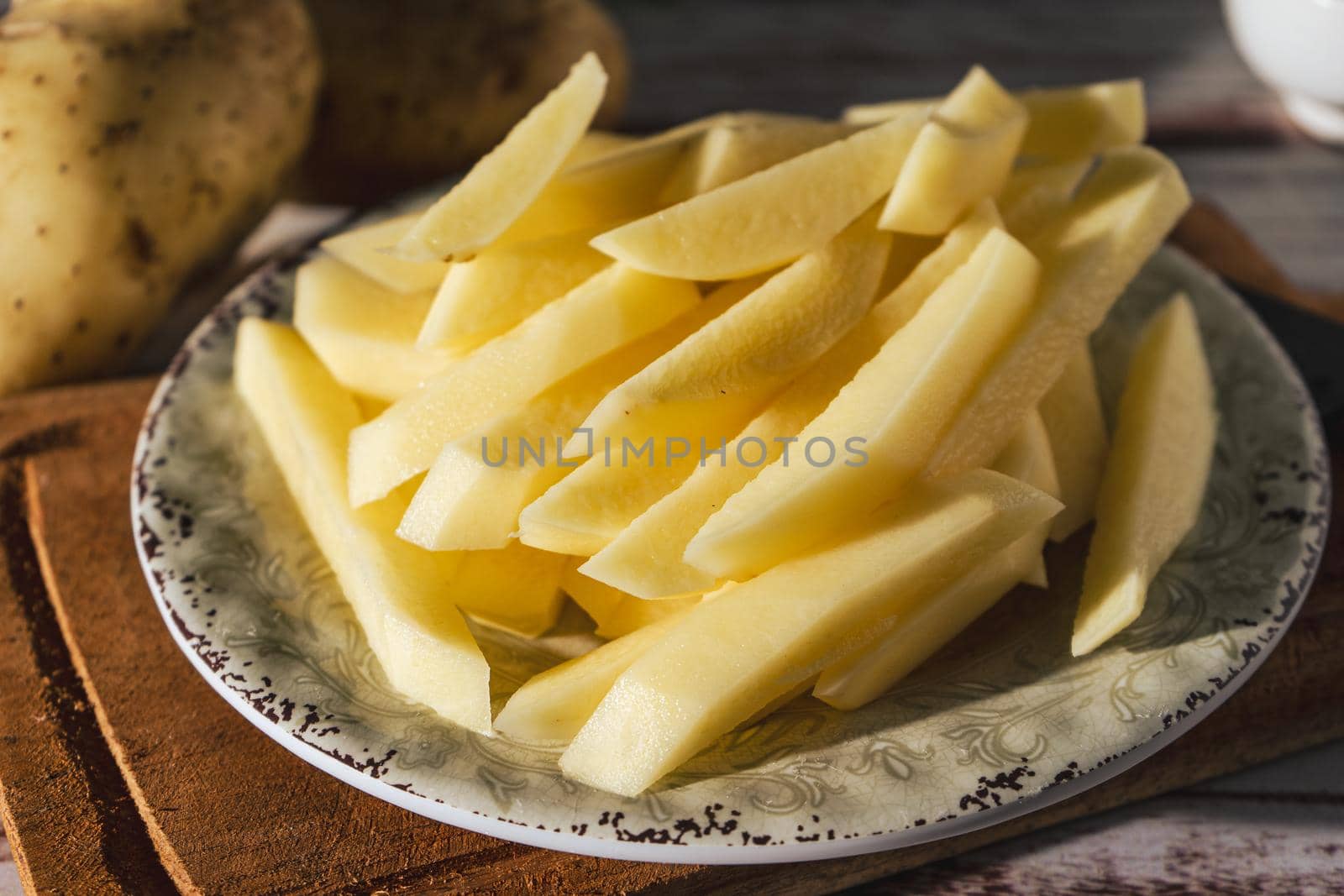 Dish with raw cane potatoes to make french fries. Chopped or high view. close-up.