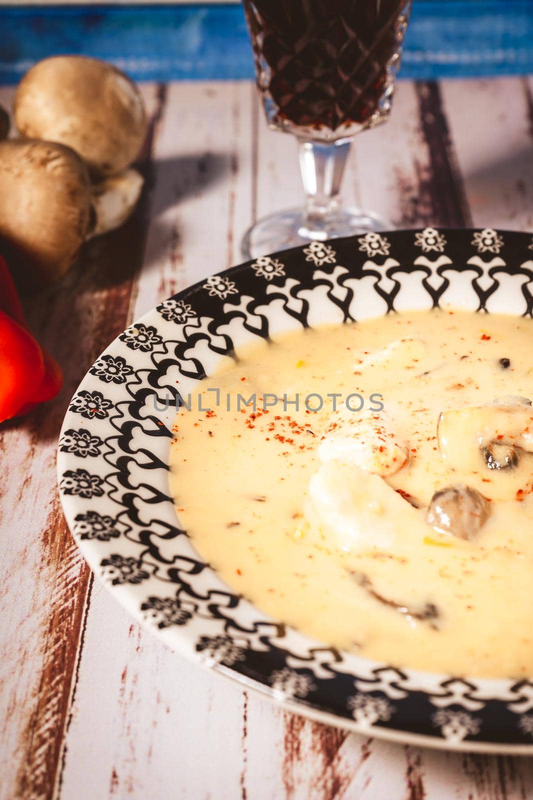 A Homemade cream of chicken and mushroom soup or French style chicken fricassee, in a soup bowl on a wooden table. High view.