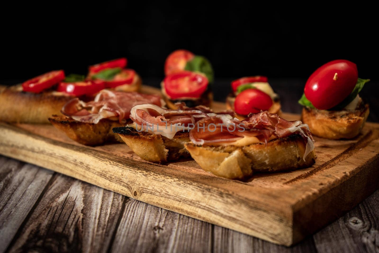 Arrangement of a selection of different tapas or bruschettas on a wooden board. Mediterranean food concept. High view.