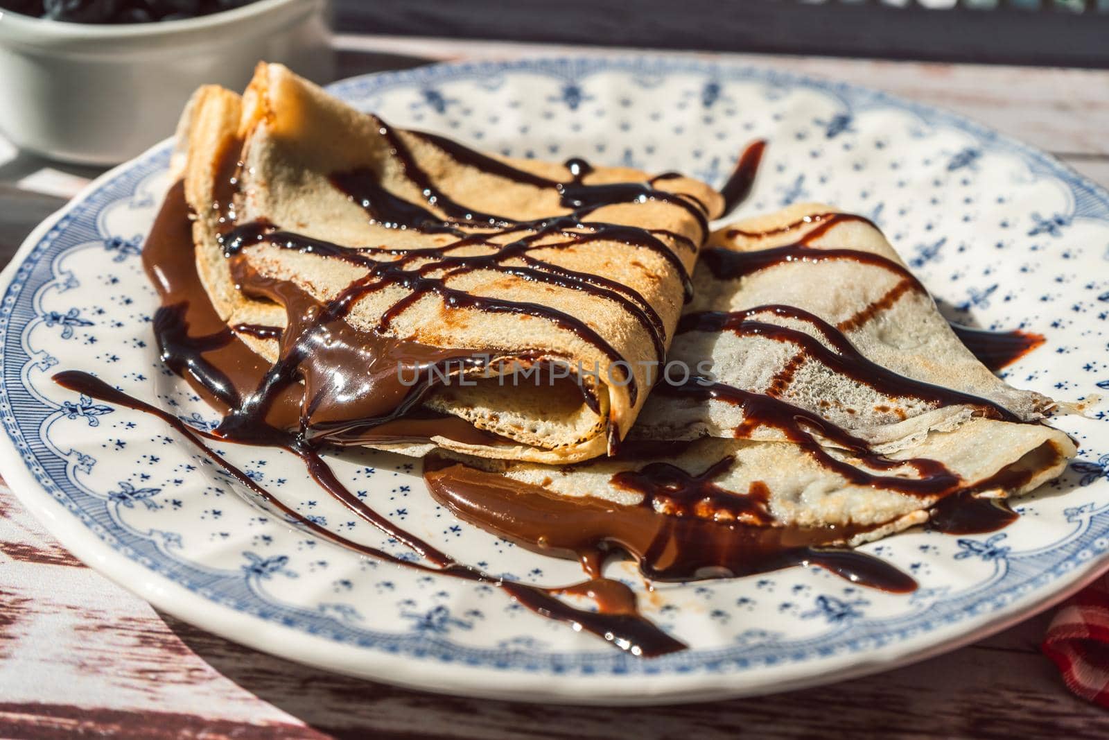 Plate two exquisite homemade pancakes or crepes filled with almond cream and chocolate with chocolate threads covering.