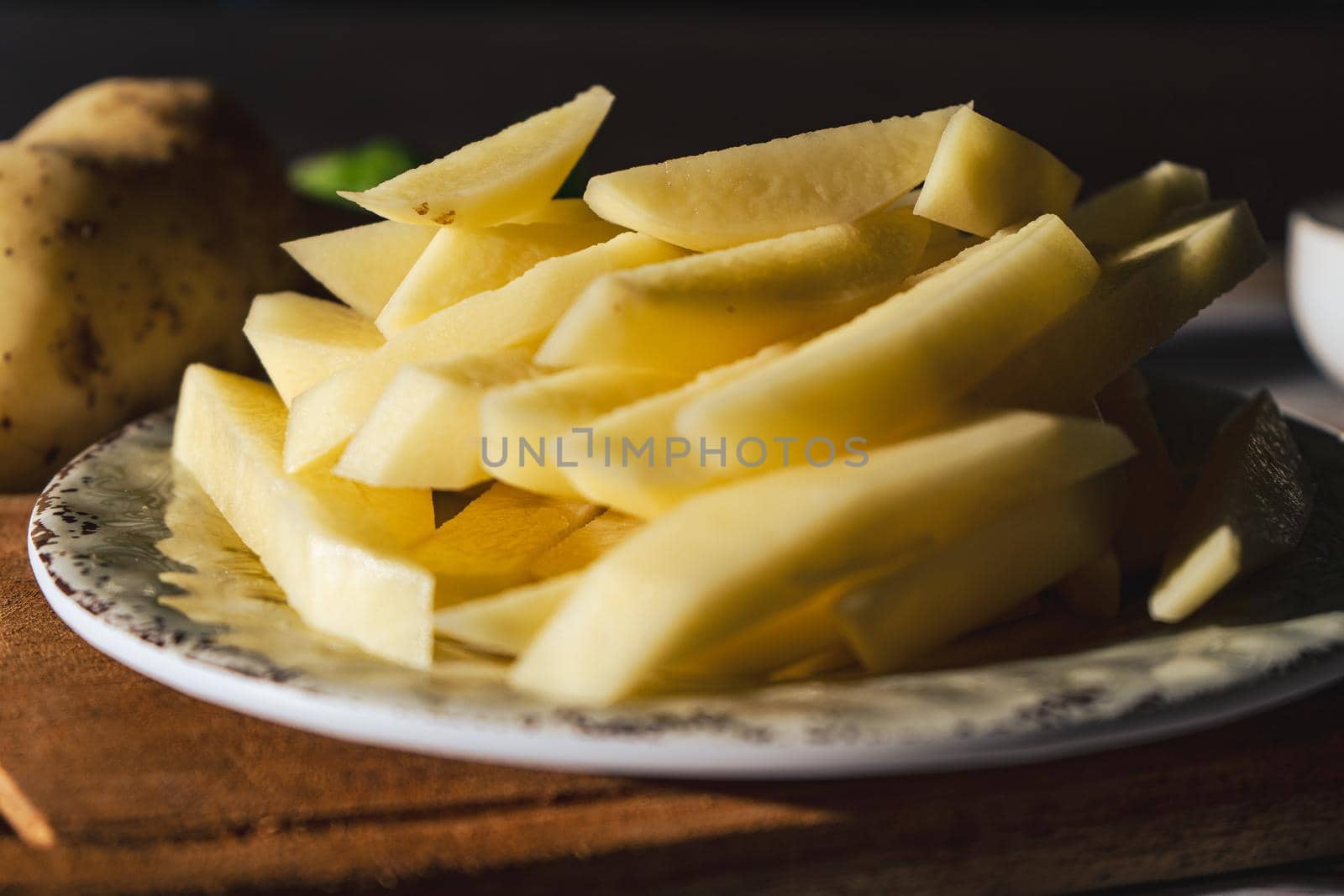 Dish with raw cane potatoes to make french fries. Chopped or high view. close-up.