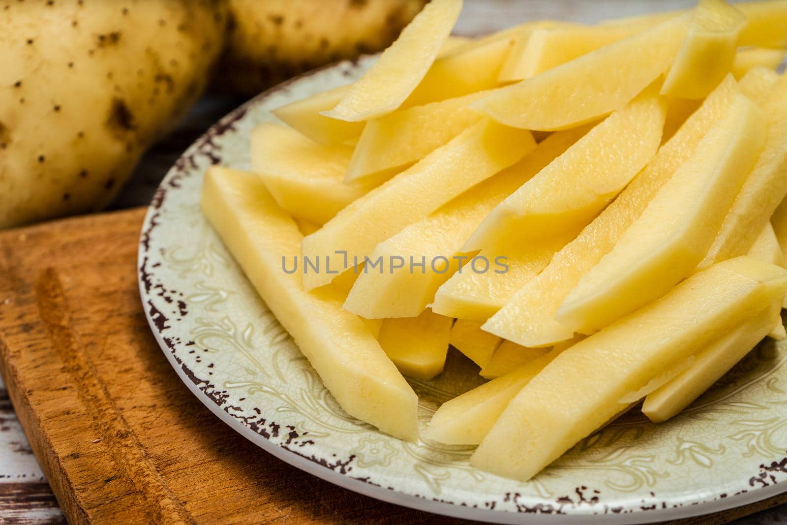 Dish with raw cane potatoes to make french fries. Chopped or high view. close-up.
