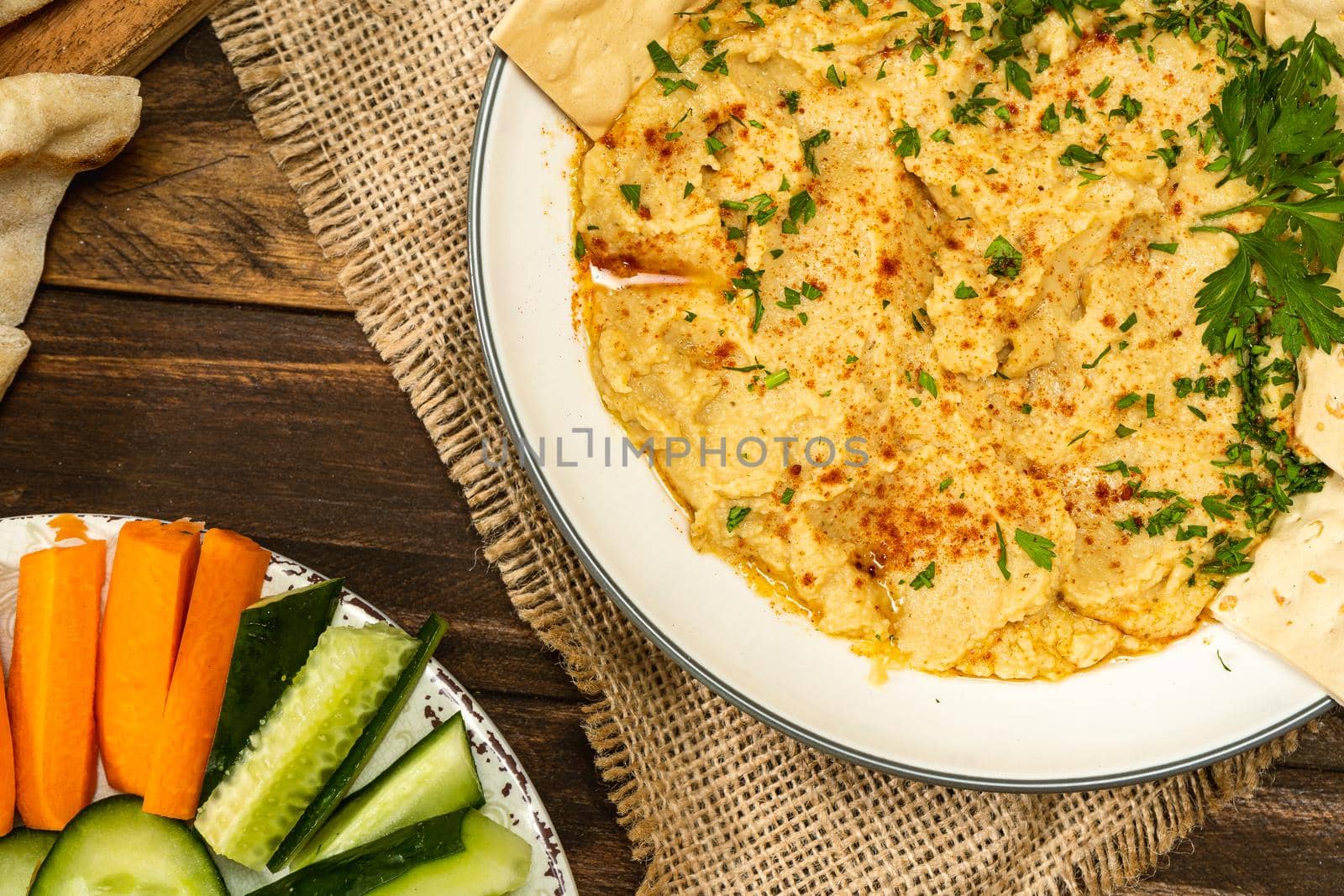 View of a bowl with homemade Hummus with crackers and in another bowl carrots and other vegetables. Fresh, healthy and natural food concept. Copy space.
