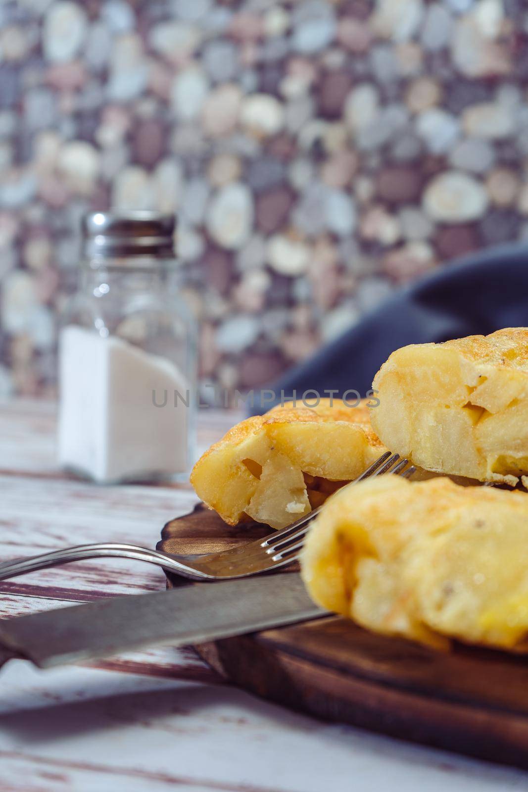 high view of a plate with a Spanish potato omelette cut in eighths on a wooden table. VErtical orientation. Traditional food.