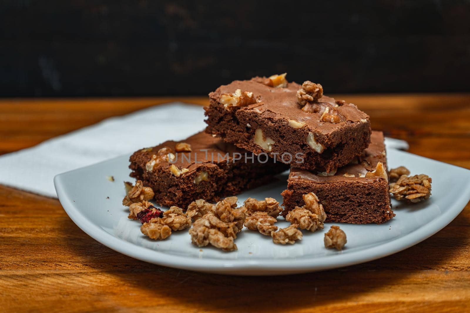 Homemade chocolate brownie squares with pecan pieces served on a white plate. Natural, healthy food concept. High view.