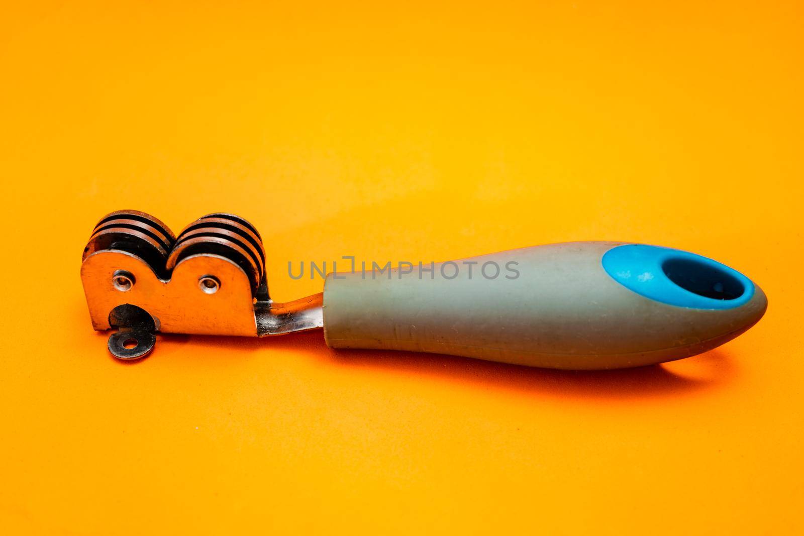 Knife sharpener isolated on an orange background. Inexpensive non-professional kitchen utensil.