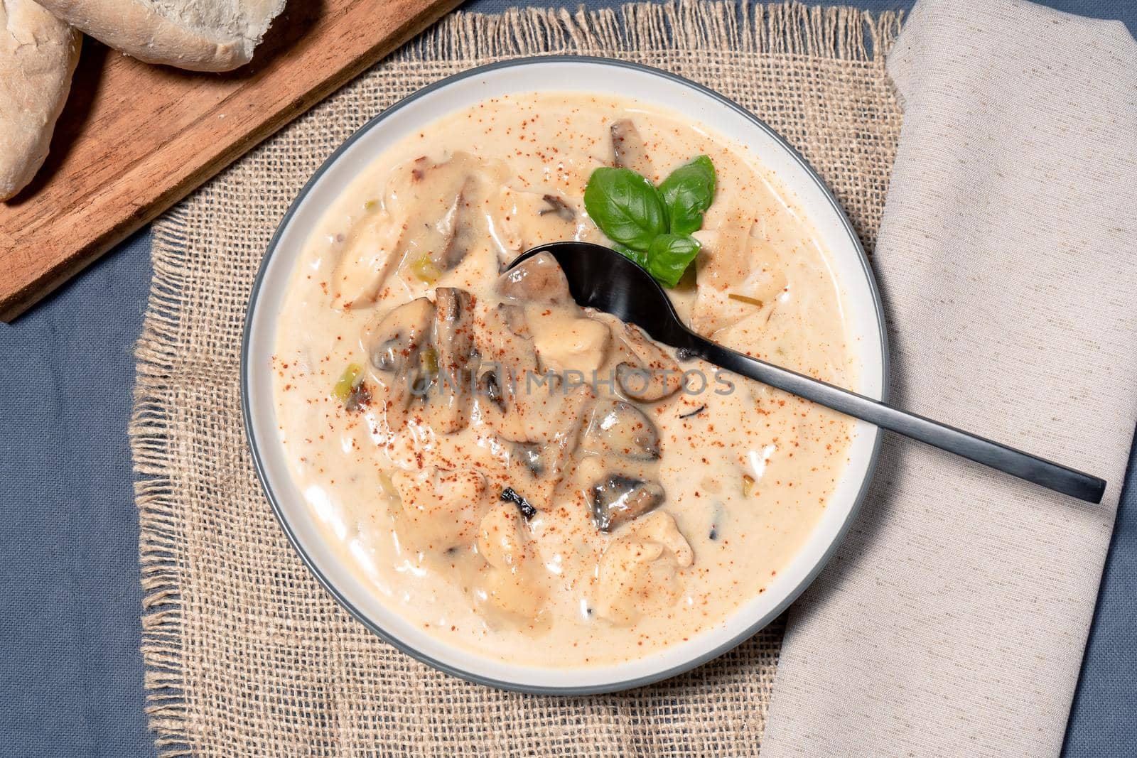 A Homemade cream of chicken and mushroom soup or French style chicken fricassee, in a soup bowl on a wooden table. Aerial view