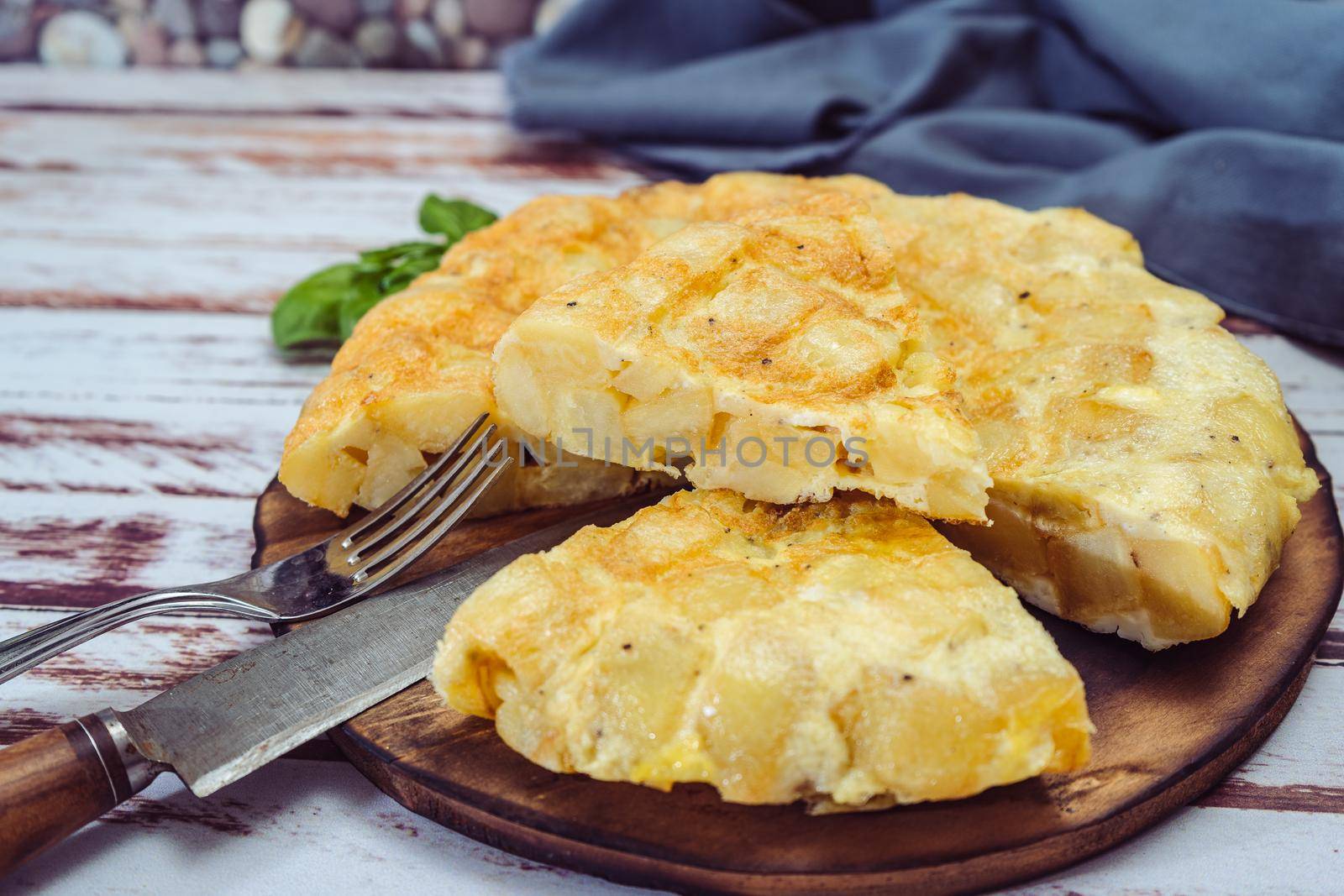 high view of a plate with a Spanish potato omelette cut in eighths on a wooden table.