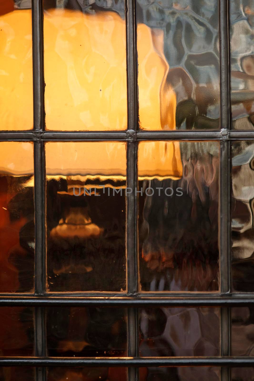 Lampshade through vintage corrugated glass window in pub by elenarostunova