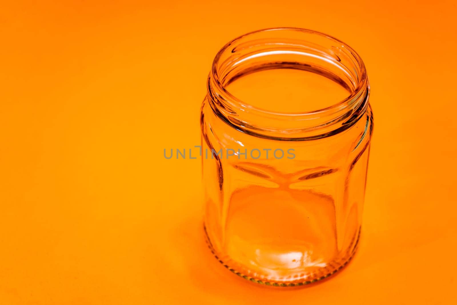 Empty hexagonal glass flask isolated on orange bottom.