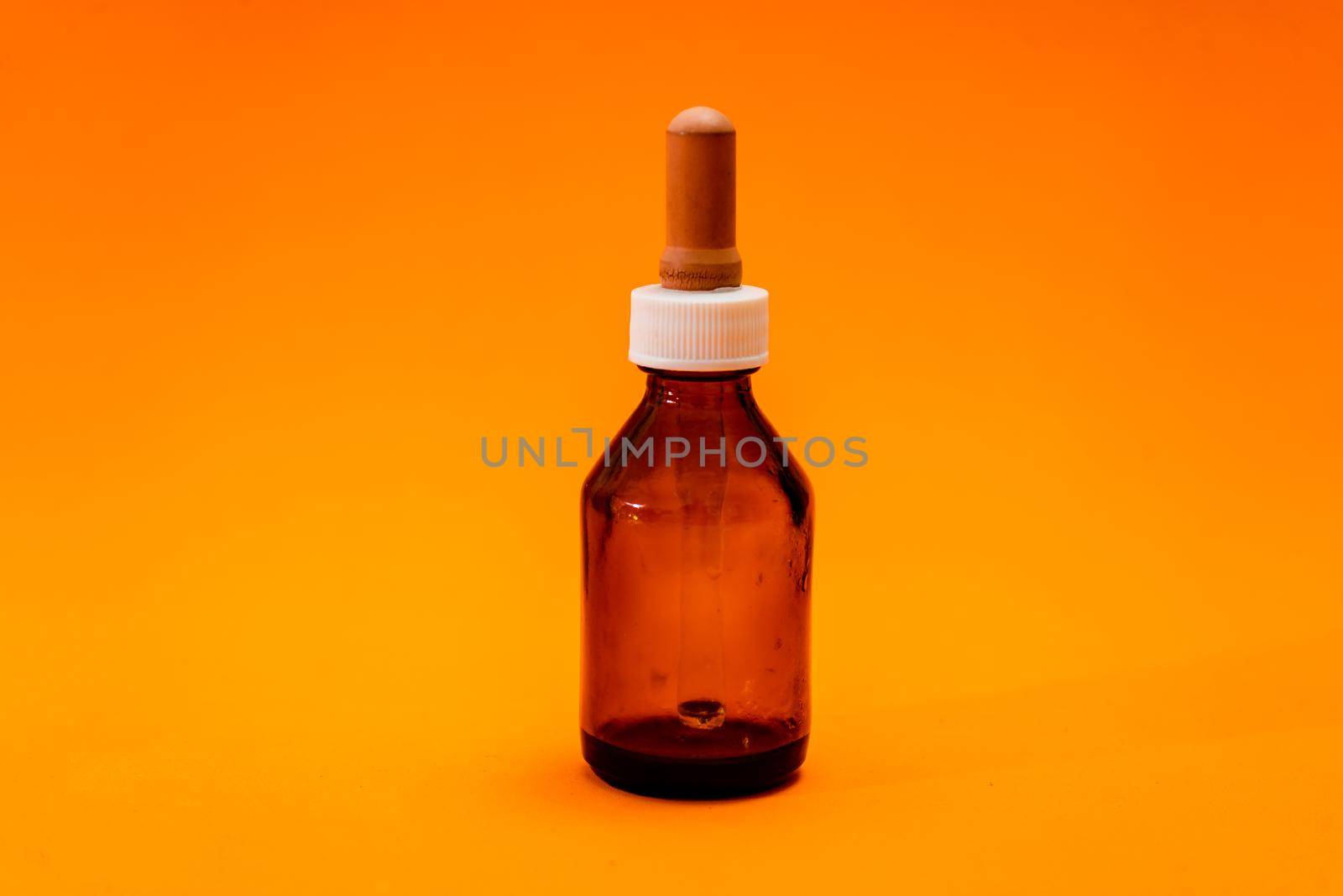 Small bottle with amber glass dropper insulated on orange background. copy space.