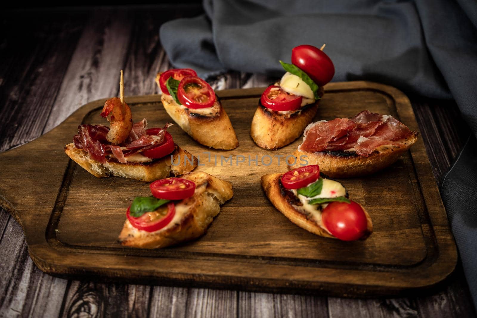 Arrangement of a selection of different tapas or bruschettas on a wooden board. Mediterranean food concept.