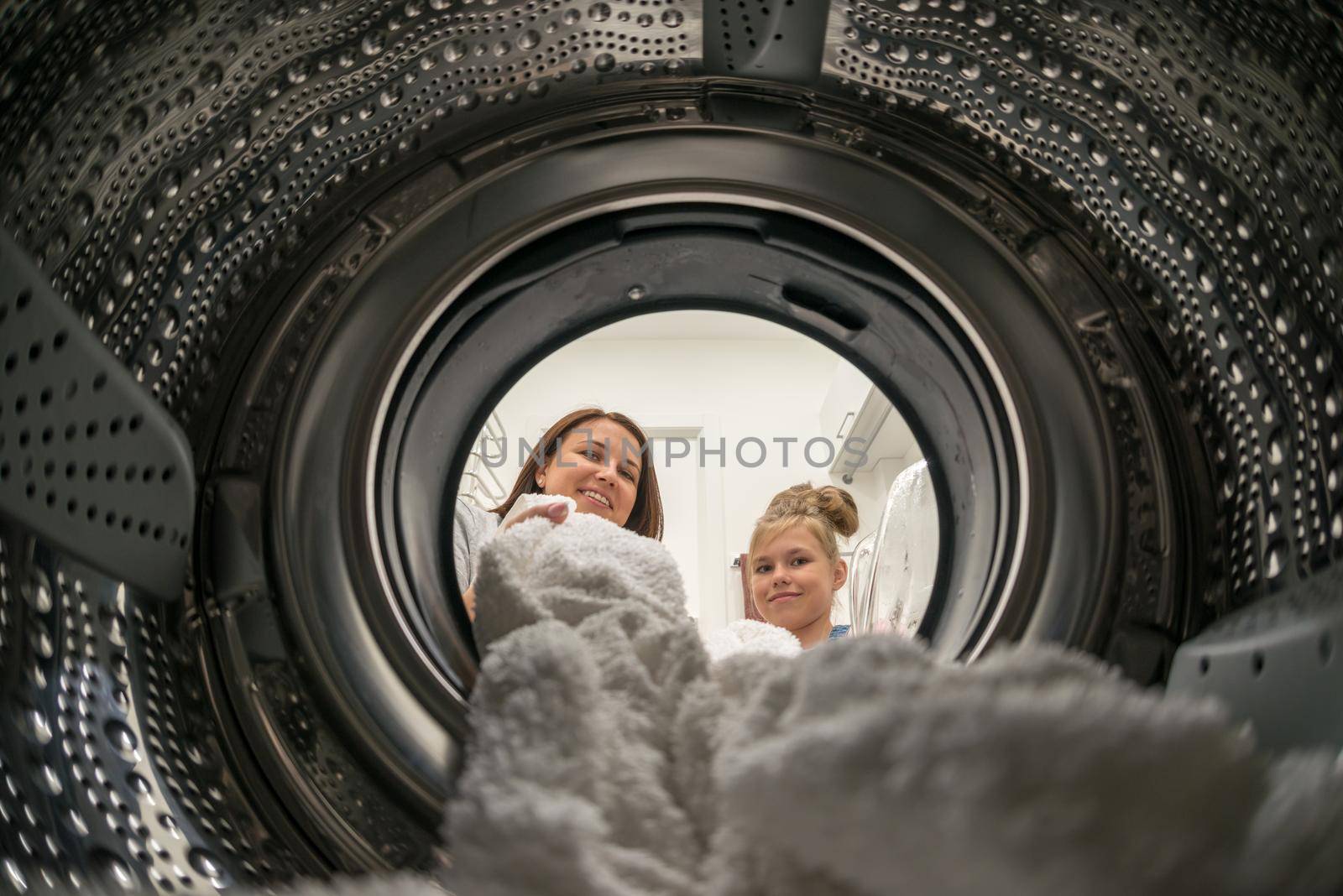 Woman Doing Laundry with daughter Reaching towel Inside Washing Machine