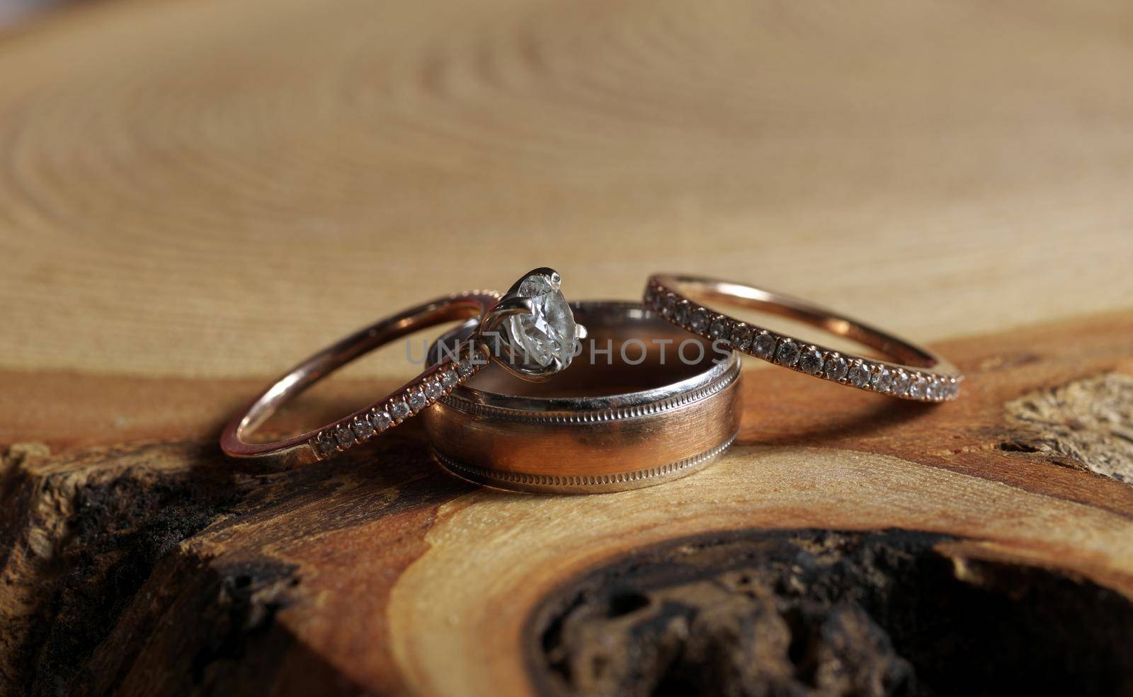 White Gold and Diamond Wedding and Engagement Rings Arranged on Rustic Wood Tree Slice. High quality photo