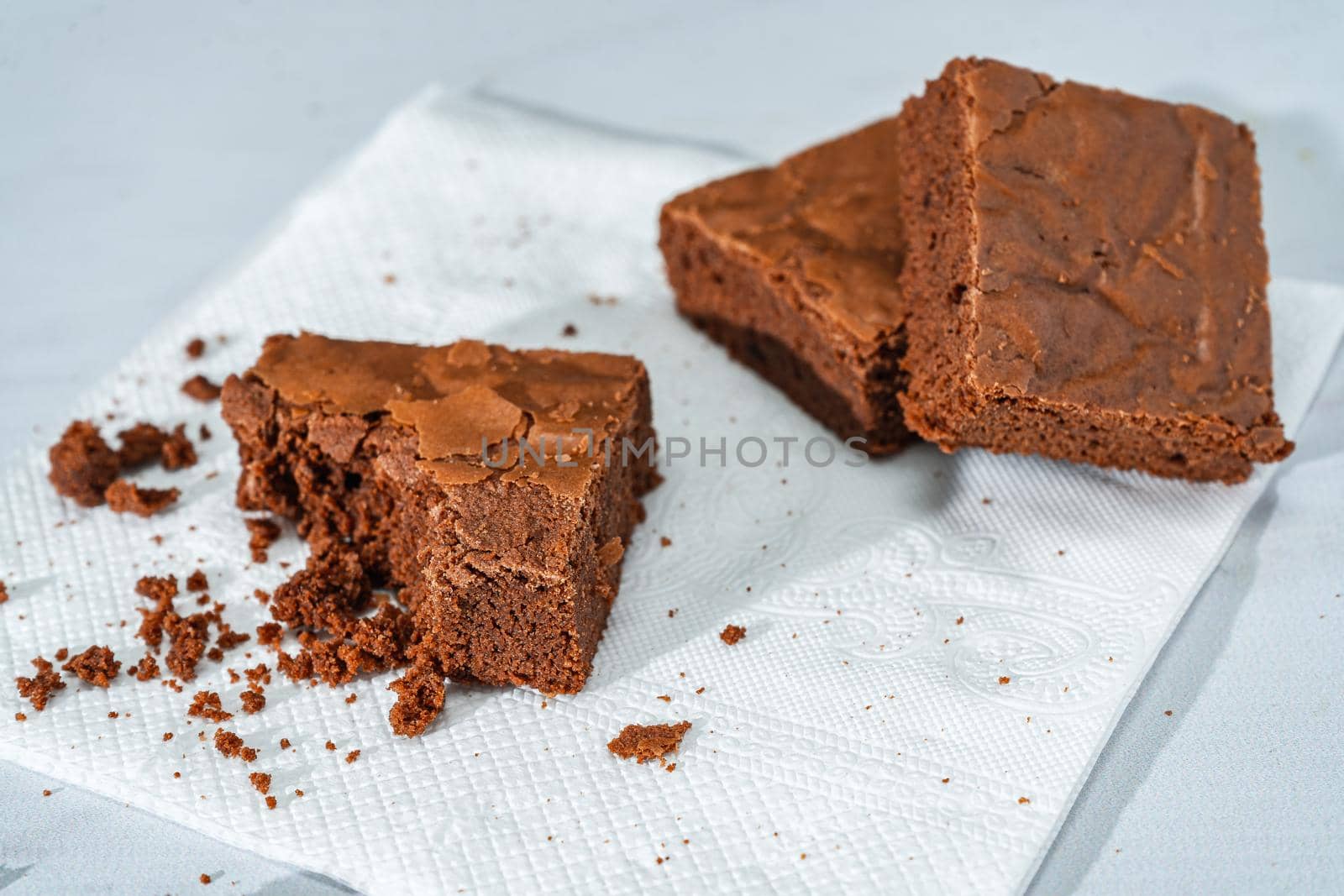 A cubes of chocolate brownies on a white plate on a marble table.