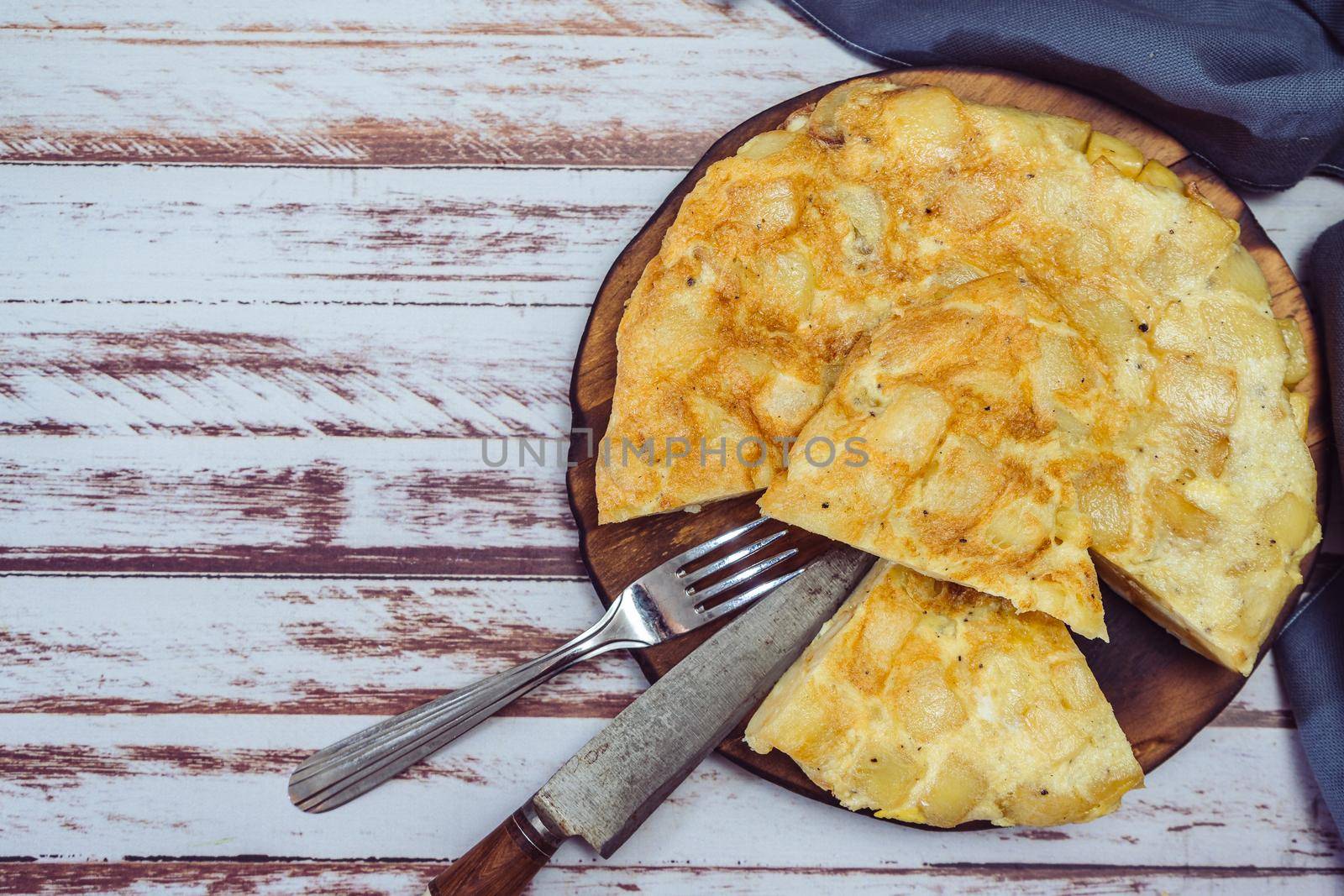 top view of a plate with a Spanish potato omelette cut in eighths on a wooden table. copy space.