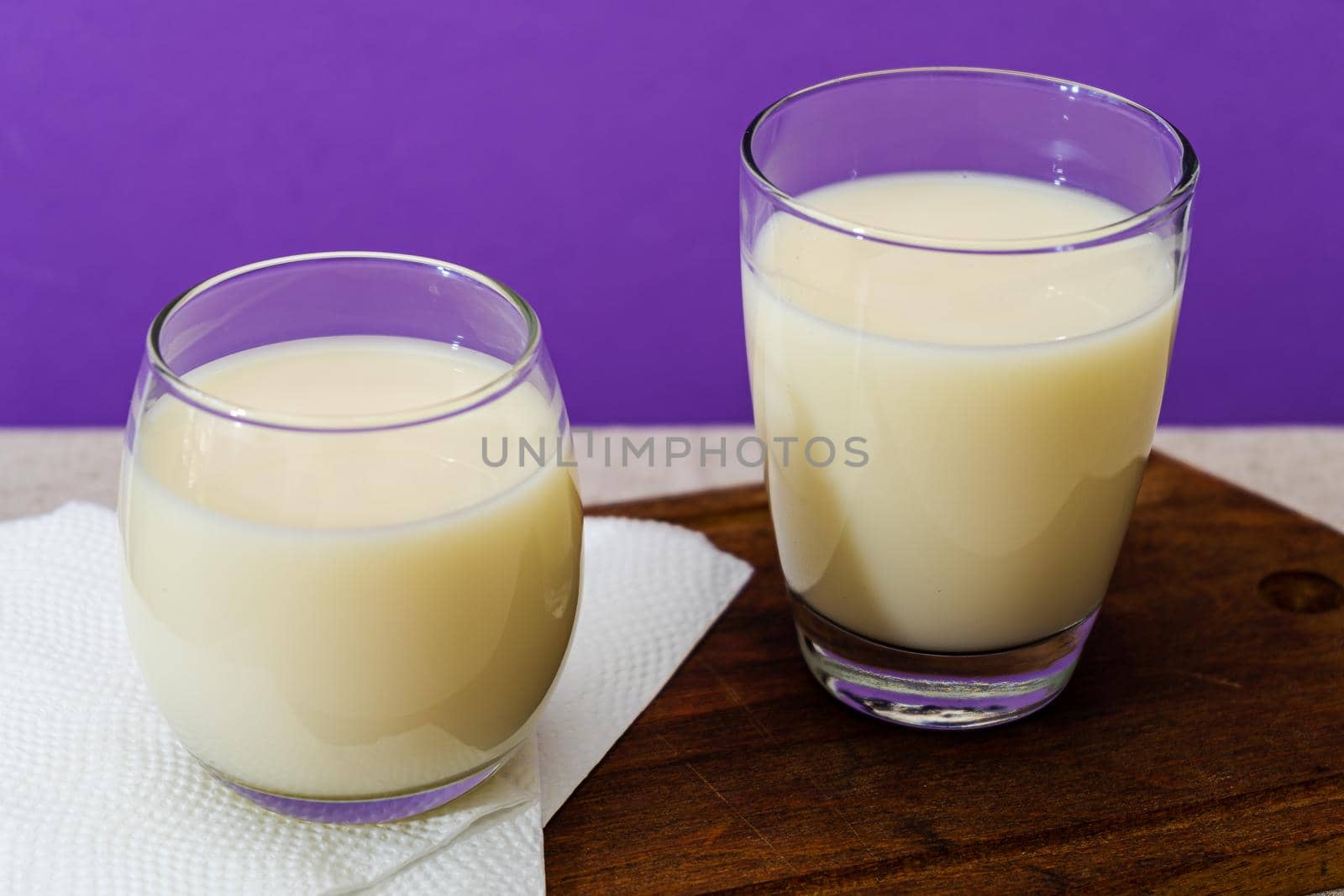 Two glasses of milk of different shape and volume on a wooden board on a table. Healthy Drink. close up