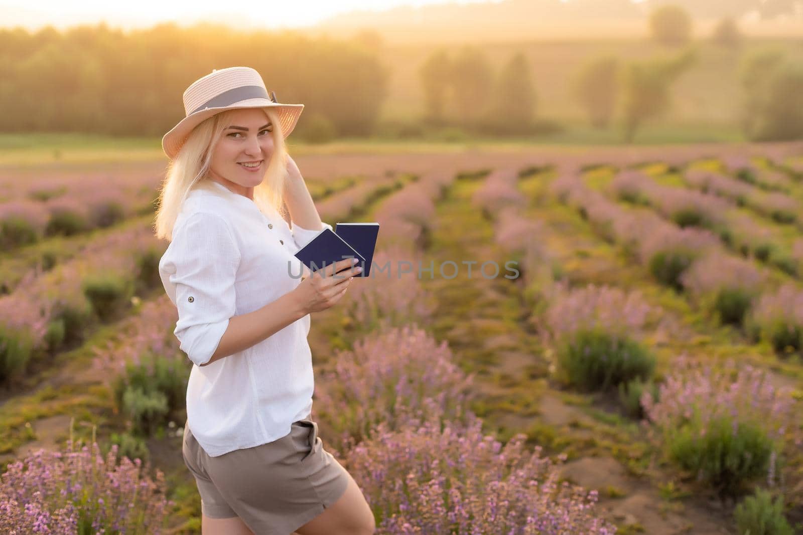 Portrait of a happy smiling woman holding passport in lavender field.