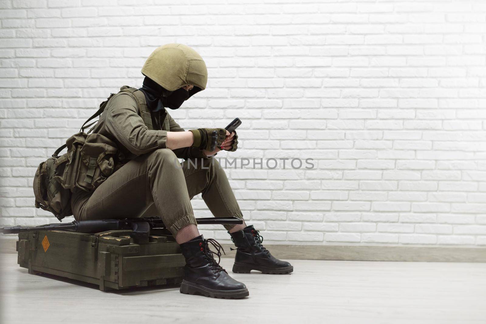 a soldier girl in a helmet is sitting and talking on a mobile phone by Rotozey