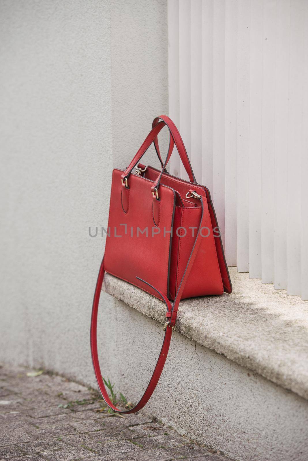 fashionable coral red Crossbody bag on the white concrete background. crossbody bag made of leather, shoulder strap