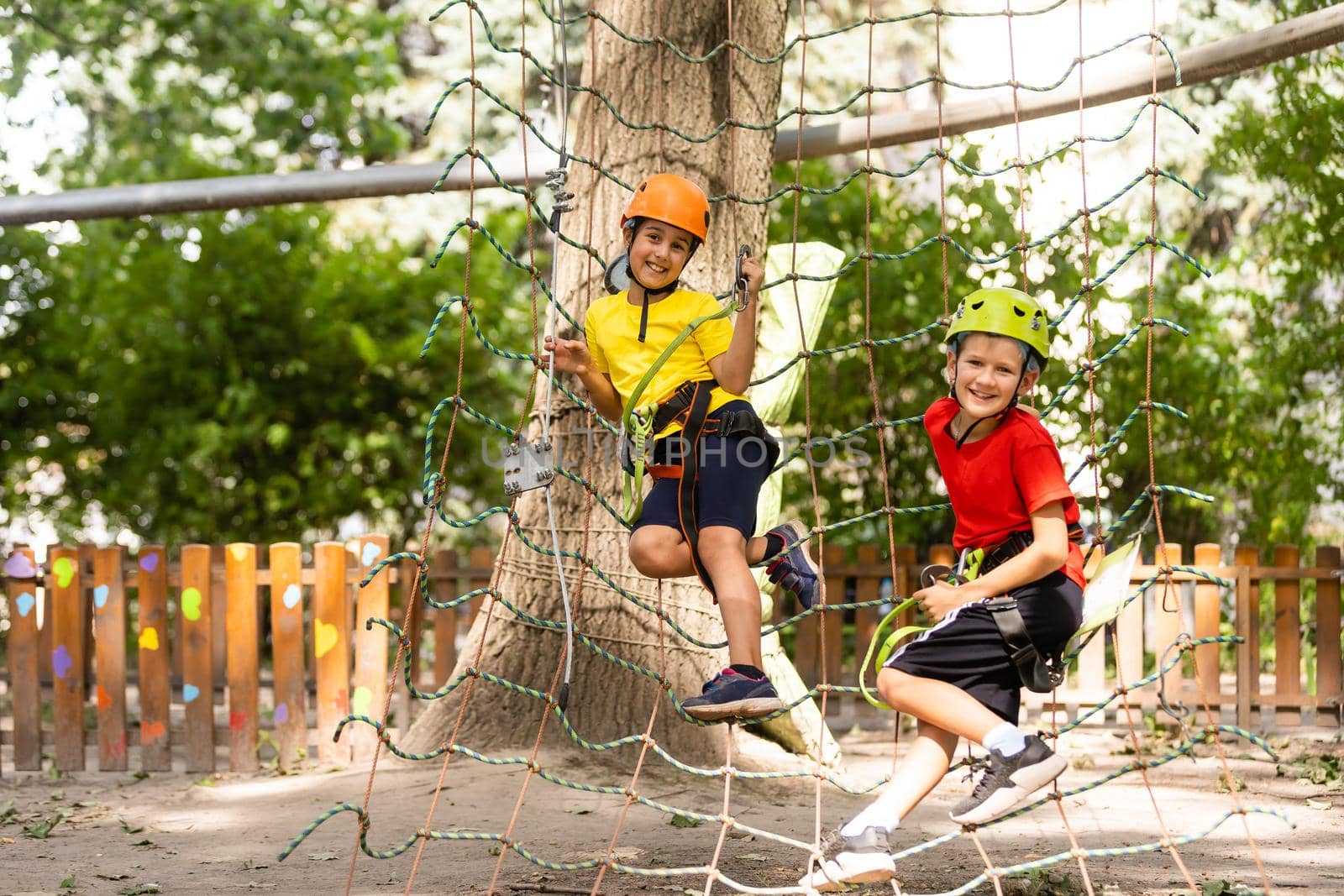 Happy child climbing in the trees. Rope park. Climber child. Early childhood development. Roping park. Balance beam and rope bridges. Rope park - climbing center.