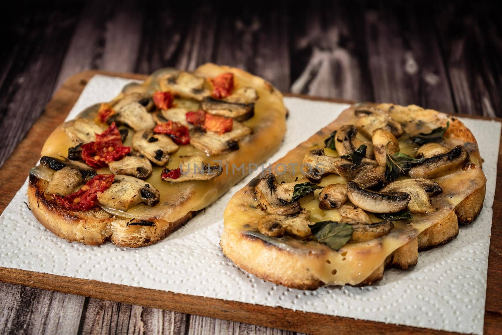 Large bruschettas with cheese, mushrooms, prosciutto and tomato in different combinations. Mediterranean food concept.
