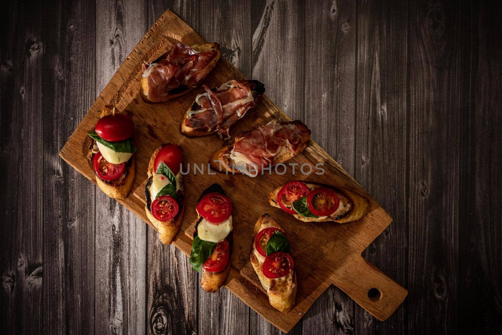 Arrangement of a selection of different tapas or bruschettas on a wooden board. Mediterranean food concept. Top View