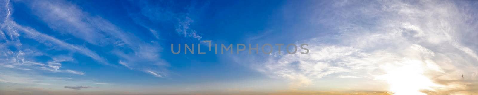 Panoramic view of blue sky with clouds and sun.