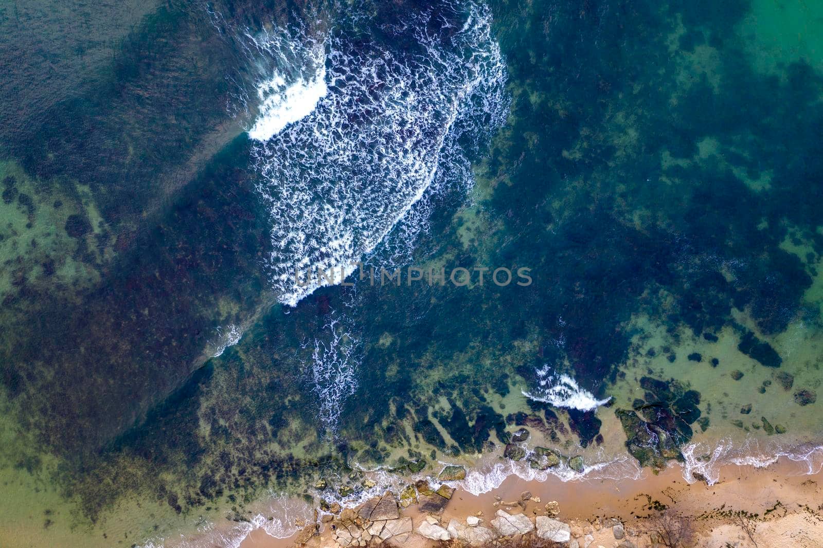 Aerial drone view of coastline surface with waves and stones. Top view