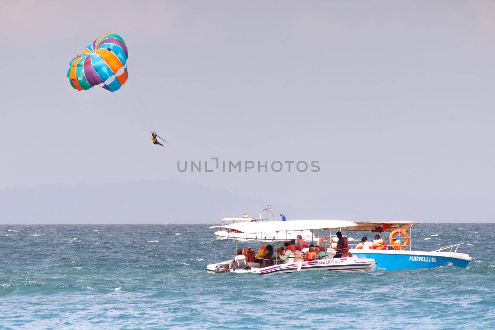 multiple boats in distance doing para gliding sailing while adventure sports like jet sking happening showing busy summer season in goa havelock andaman nicobar island india by Shalinimathur