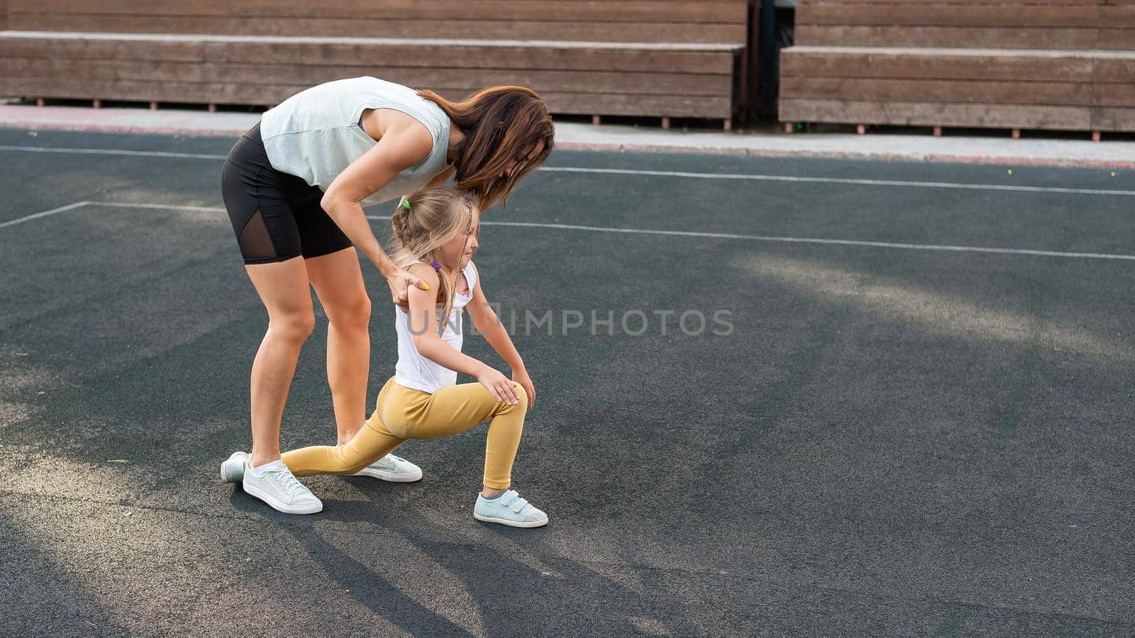 Caucasian woman goes in for sports with her daughter outdoors. A schoolgirl and her mother are running around in the stadium. by mrwed54