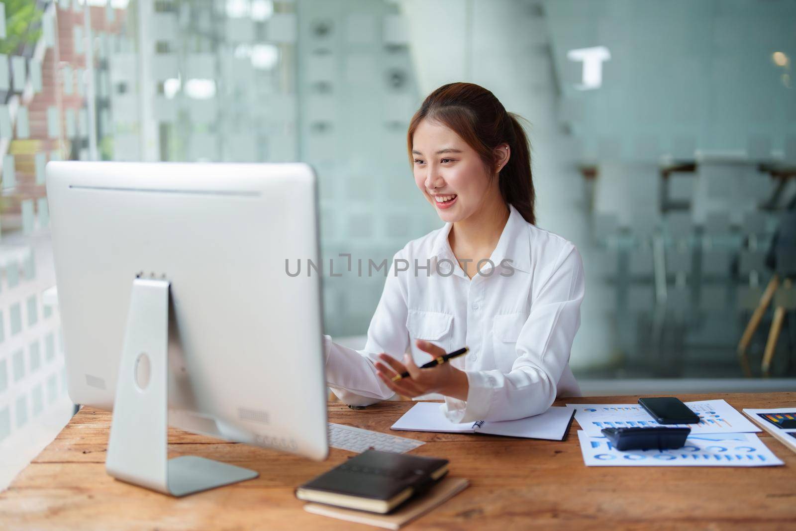 Data analysis, roadmap, marketing, accounting, auditing. Portrait of Asian businesswoman using computer in video conferencing, presenting marketing plan using statistical data sheet at work. by Manastrong