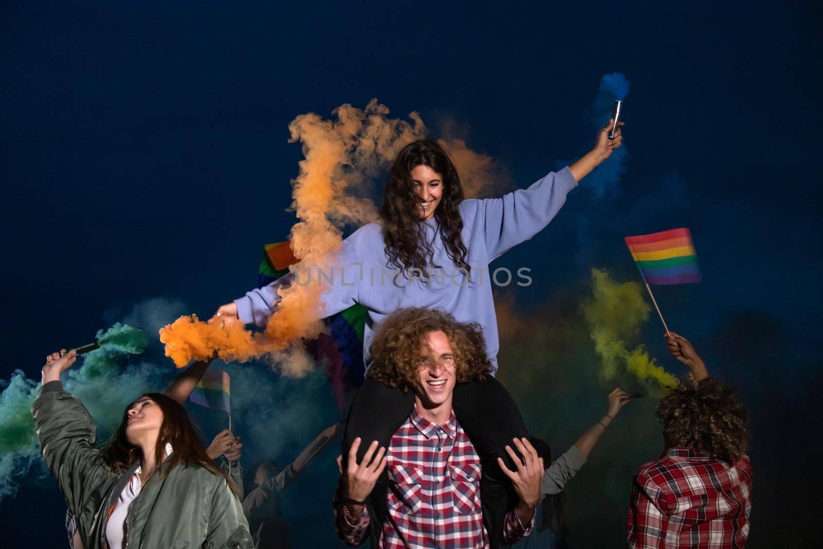 Happy group of people dancing and celebrating LGTB rights want rainbow flag in coloured smoke. Celebration and pride concept.