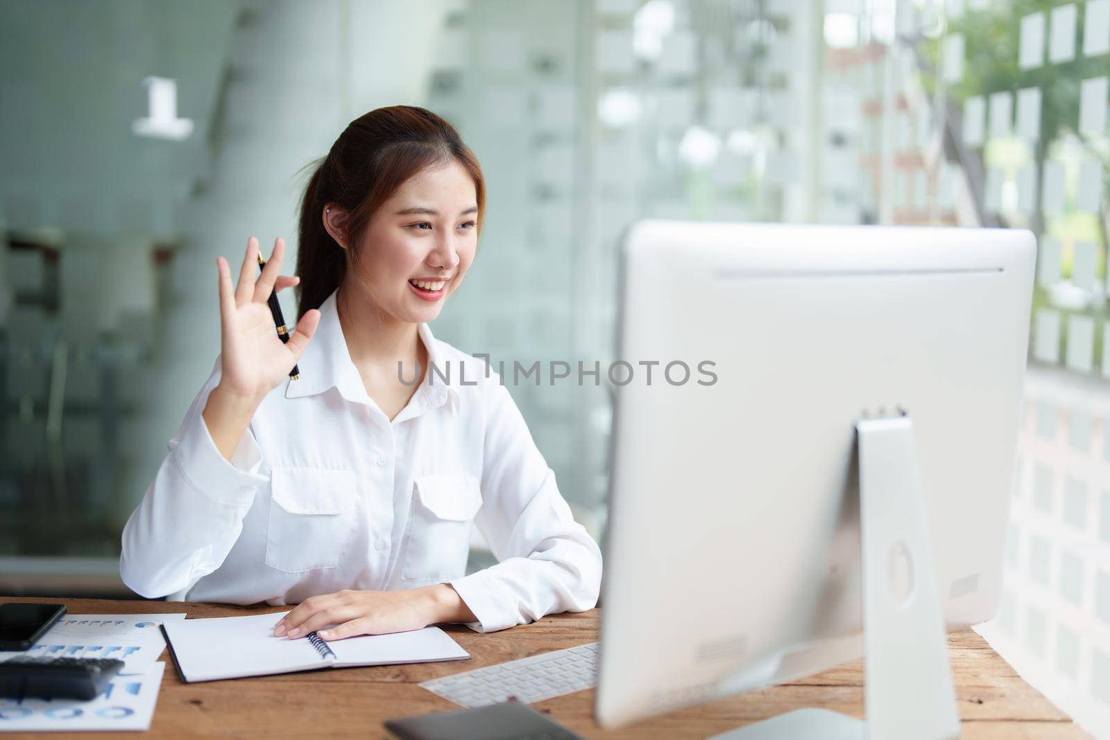 Data analysis, roadmap, marketing, accounting, auditing. Portrait of Asian businesswoman using computer in video conferencing, presenting marketing plan using statistical data sheet at work. by Manastrong