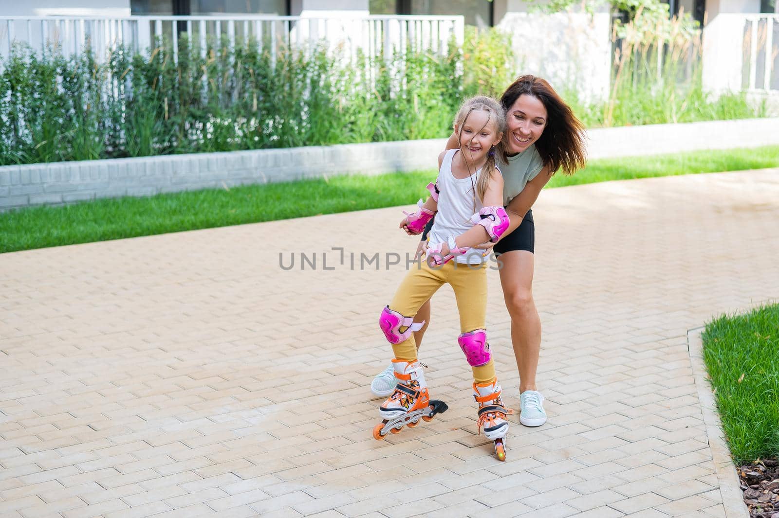 Caucasian woman teaches her daughter to skate on roller skates. by mrwed54