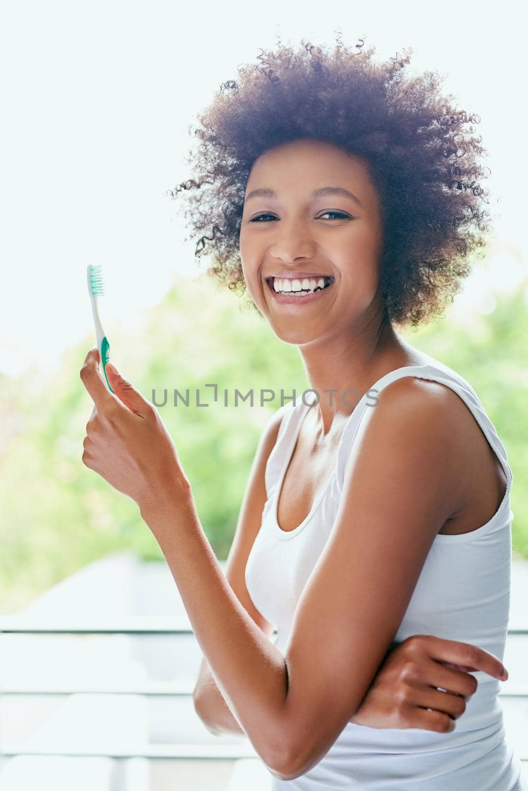Cropped shot of an attractive young woman brushing her teeth in the bathroom at home.