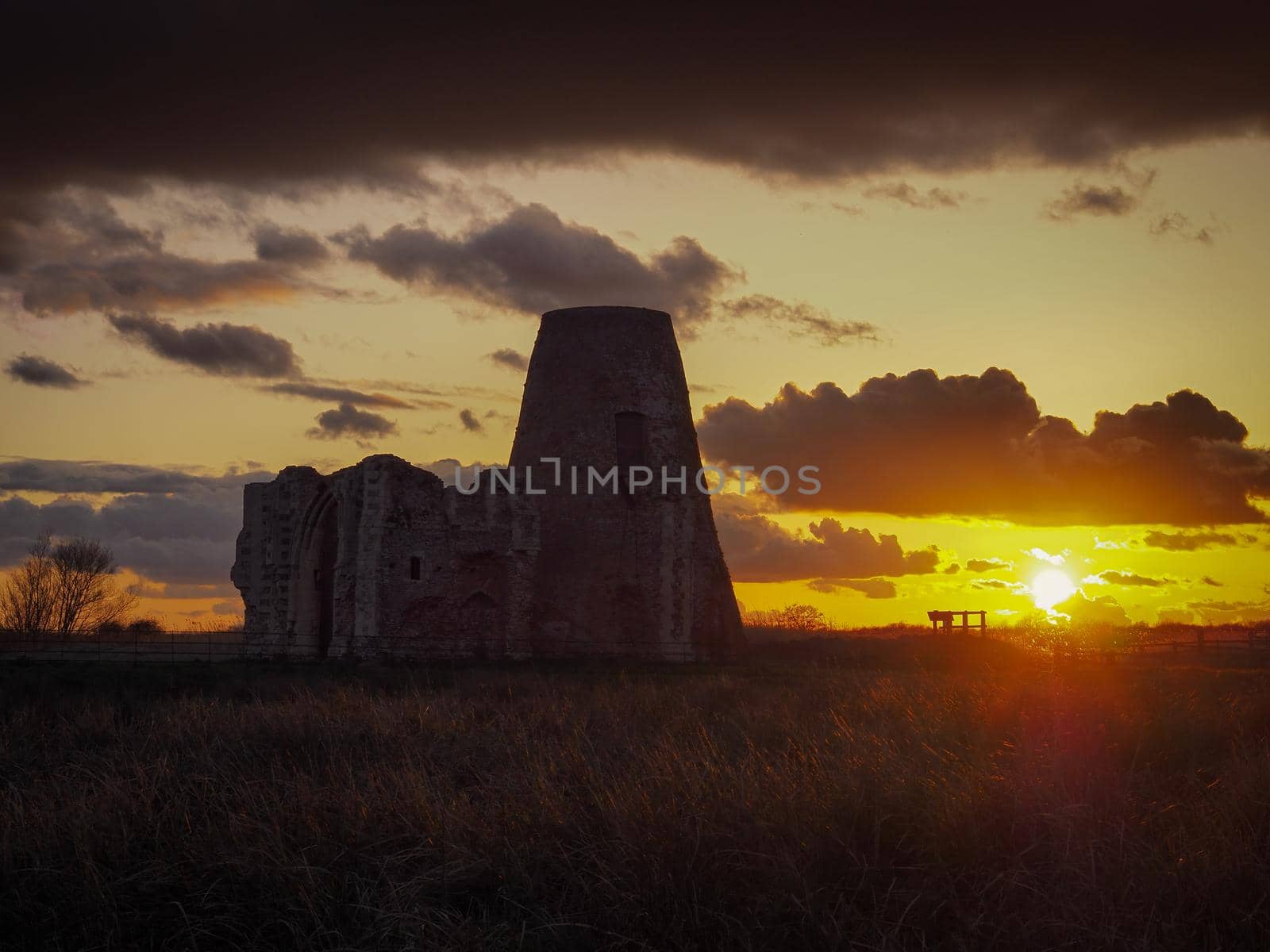 Beautiful orange sunset lighting up the clouds over the ruins of St. Benet's Abbey, near Great Yarmouth, Norfolk, UK