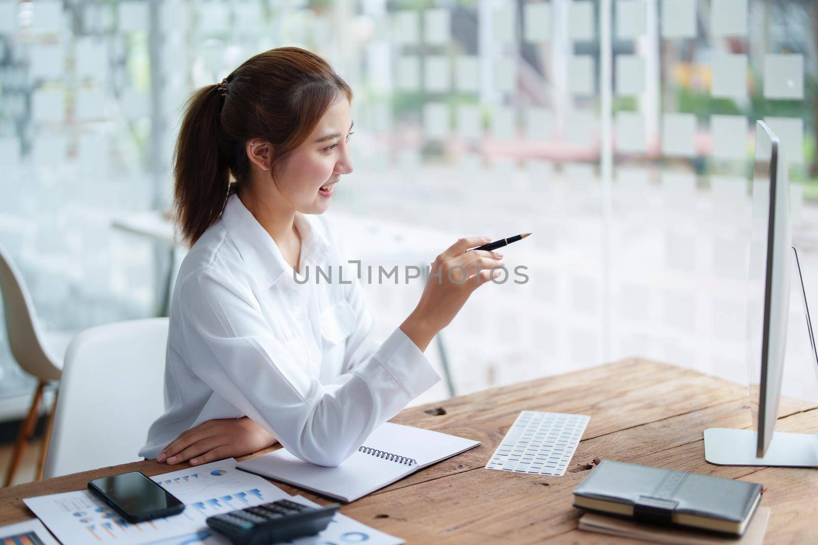 Data analysis, roadmap, marketing, accounting, auditing. Portrait of Asian businesswoman using computer in video conferencing, presenting marketing plan using statistical data sheet at work. by Manastrong