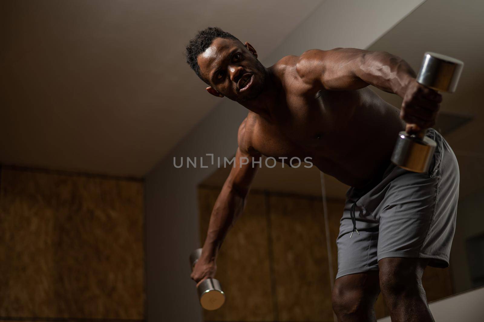 Attractive african american man doing arm exercises with dumbbells