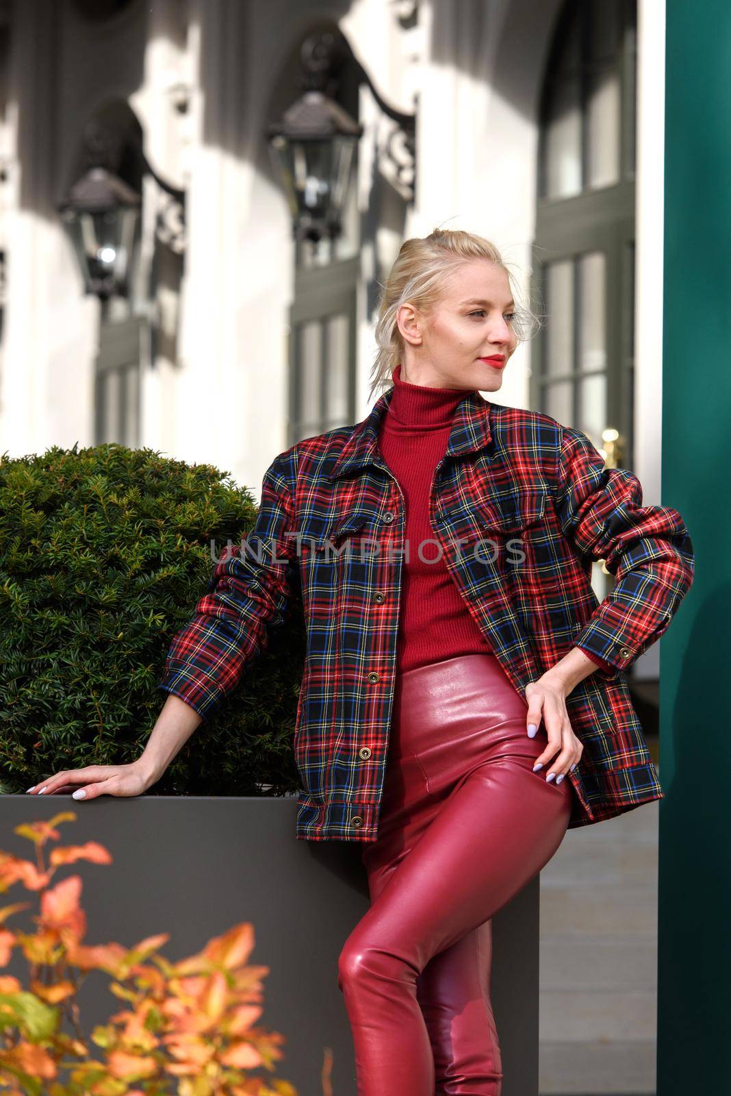 fashionable blonde girl with a red lipstick posing outdoors . Dressed in a red leather leggings, turtleneck and checkered jacket. fit figure by Ashtray25