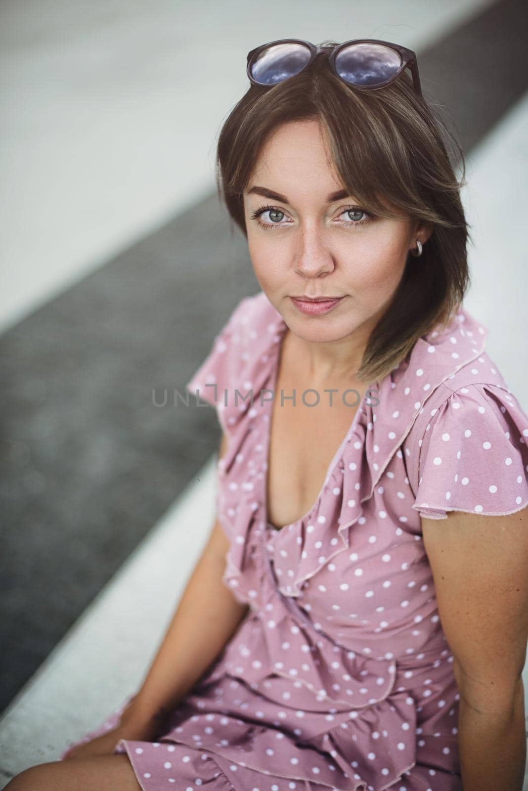 Portrait of a young beautiful brunette posing on the street in a soft pink sundress by Ashtray25