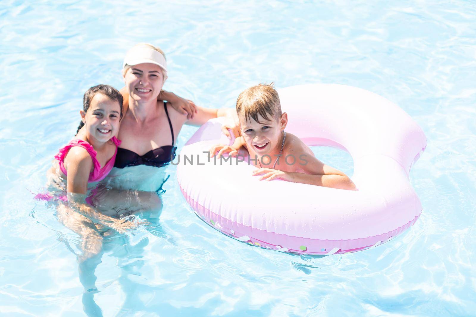 Young mother with children sitting on the edge of the pool.