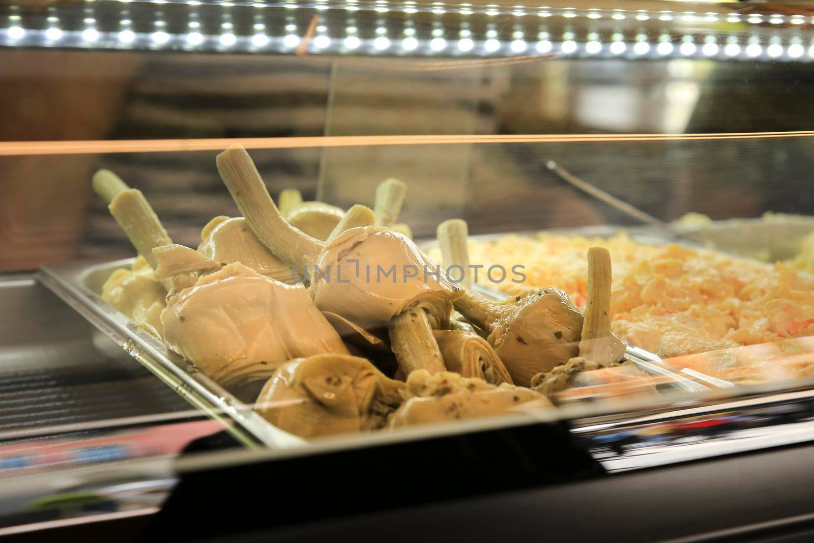 Artichokes in olive oil next to russian salad on a Spanish Bar counter