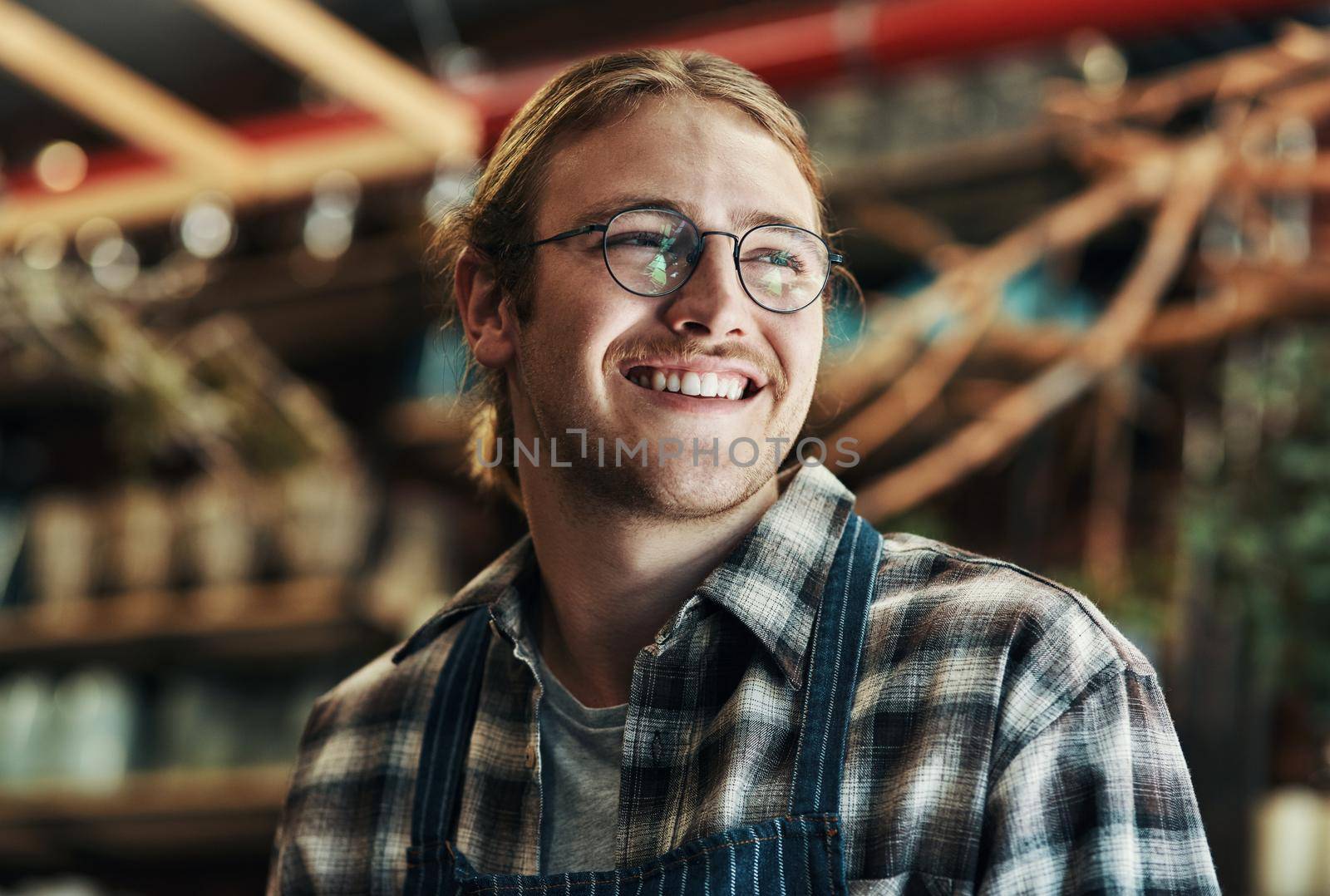 Cropped shot of a handsome and happy young florist working inside his plant nursery.