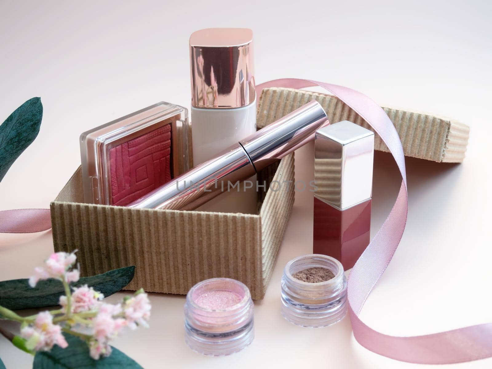 a set of cosmetics for a female face and eye makeup in a brown craft box on a pink background. photo