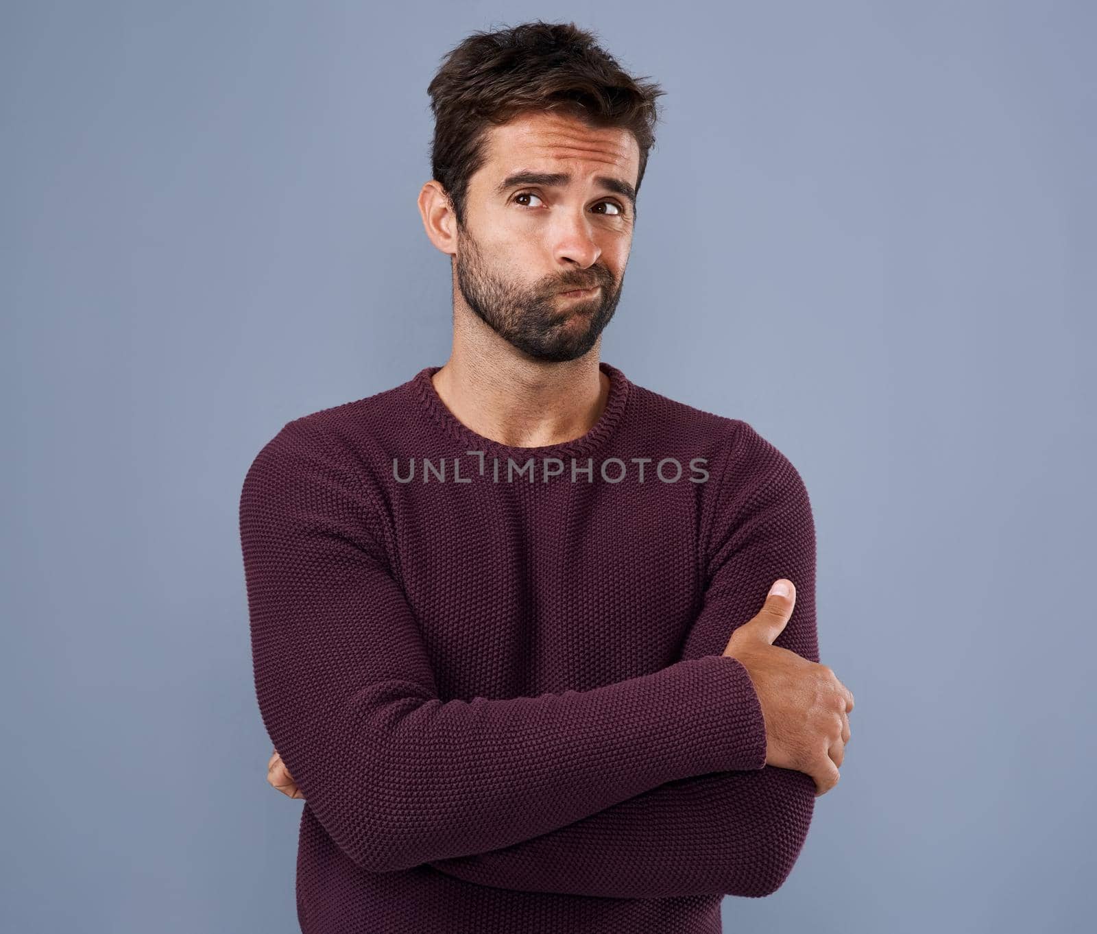 Studio shot of a handsome young man looking thoughtful against a gray background.