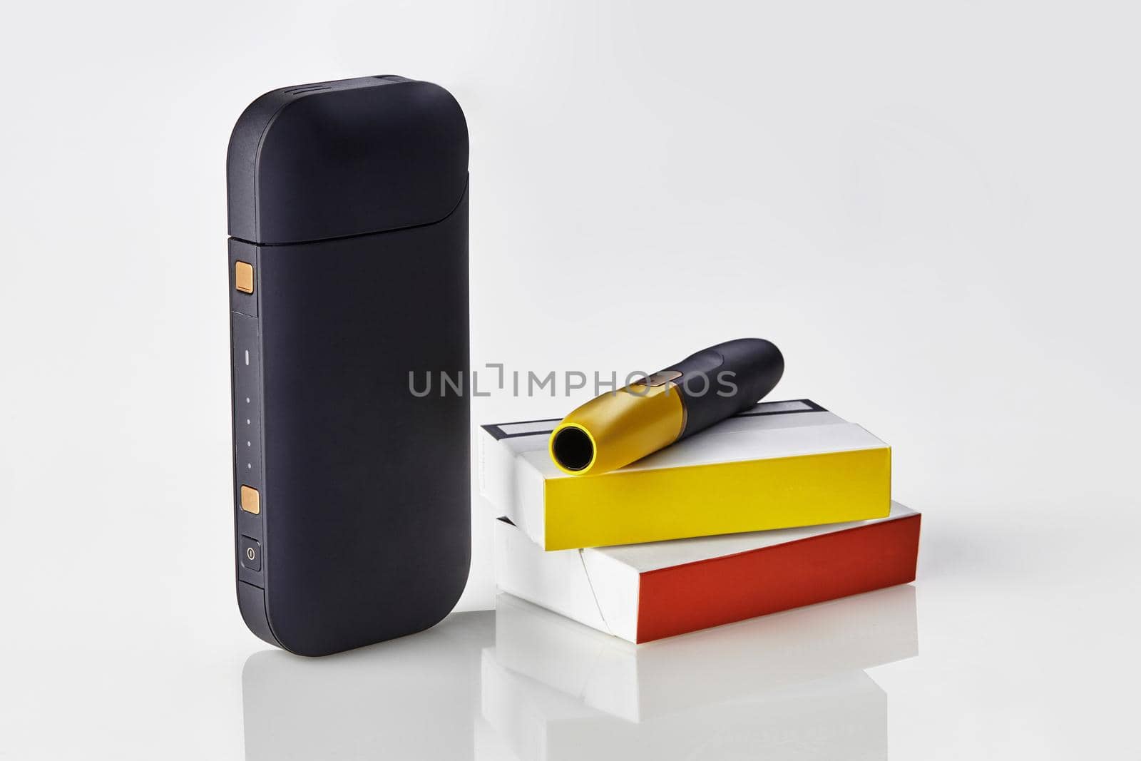 New generation black electronic cigarette is on packs with red and yellow sides, battery, isolated on white. New technology. Heating tobacco system. Template place for your text, image. Close up