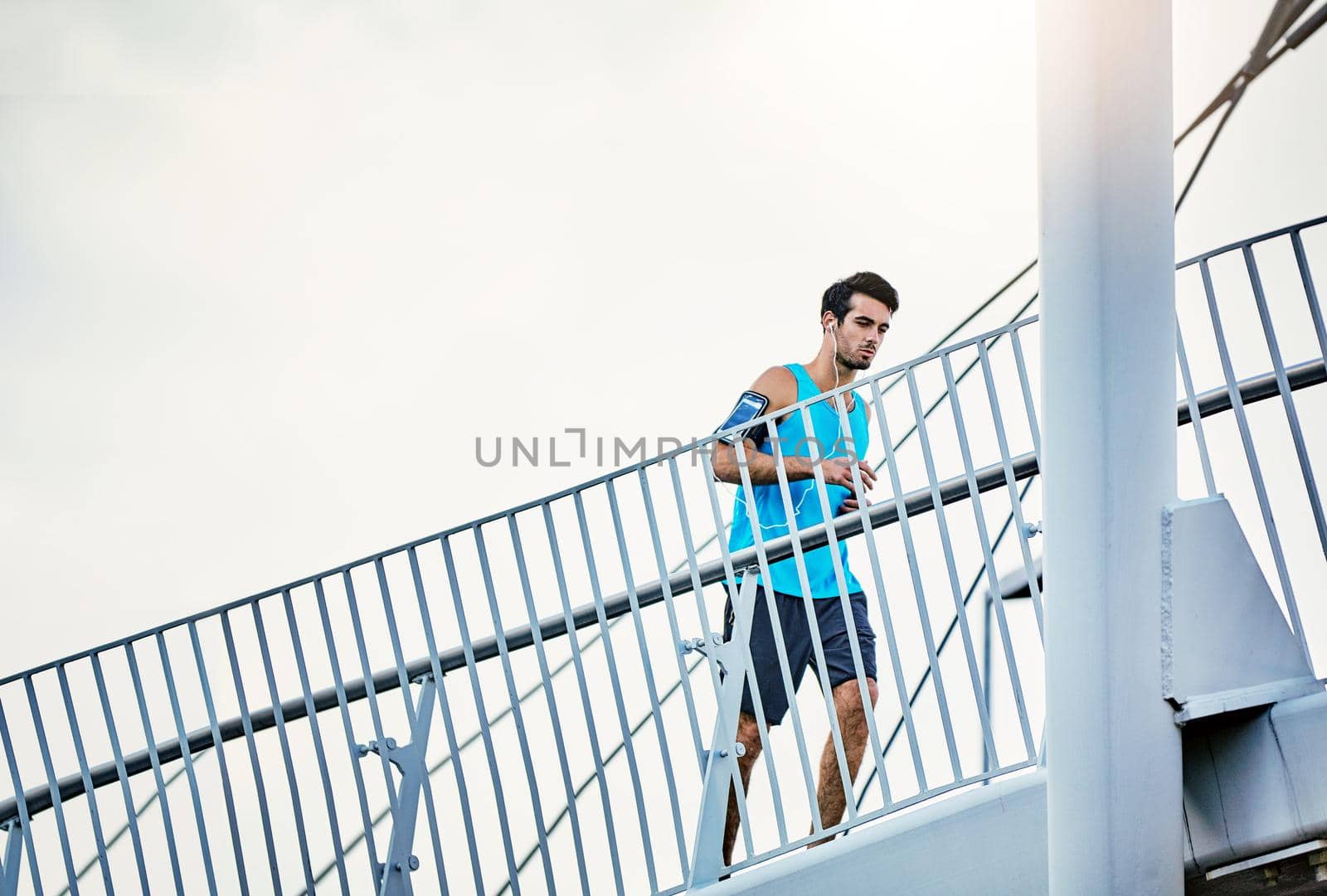 Upping his fitness levels. Low angle shot of a handsome young man working out in the city. by YuriArcurs